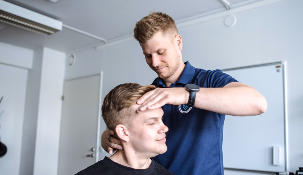 Kiropraktikko tutkii asiakkaan niskaa ja päätä
