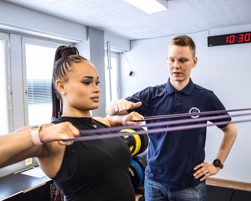 Naprapaatti Lauri Koho ohjaa asiakasta vastuskuminauhaharjoituksessa