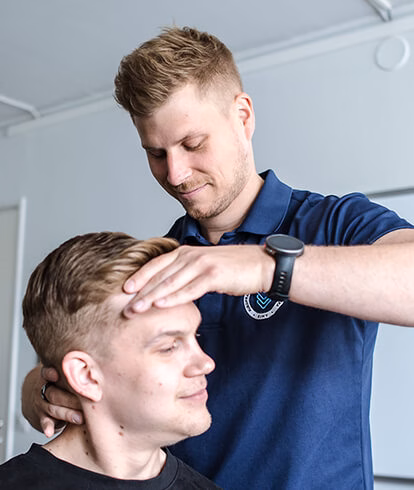 Kiropraktikko Tuomo Pieti tutkii asiakkaan niskaa ja päätä