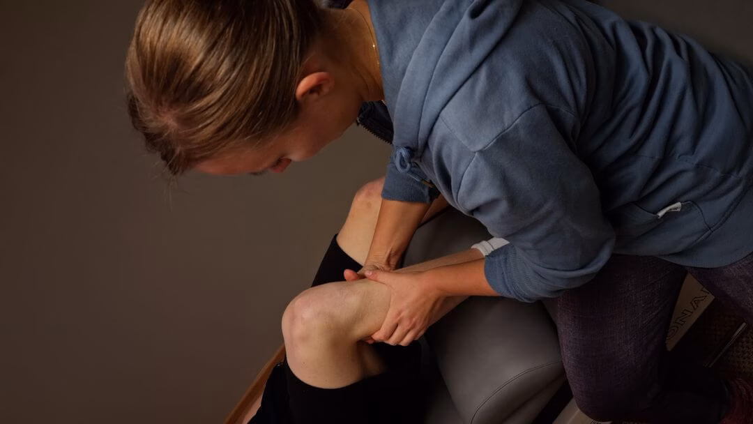 Osteopaatti Sara Vuoristo hoitaa asiakkaan polvea